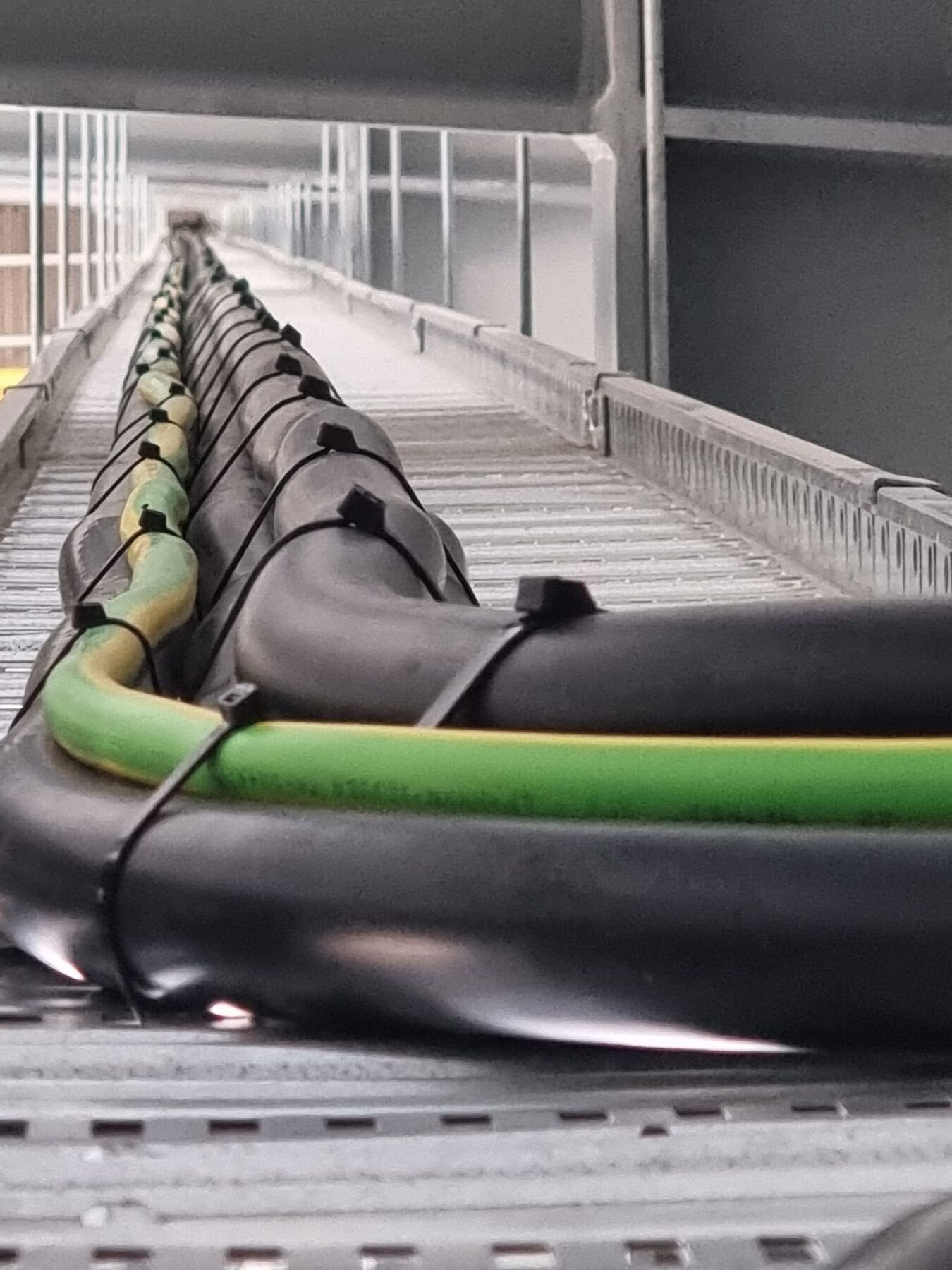 Close-up view of large electrical cables secured on a cable tray inside an industrial facility.